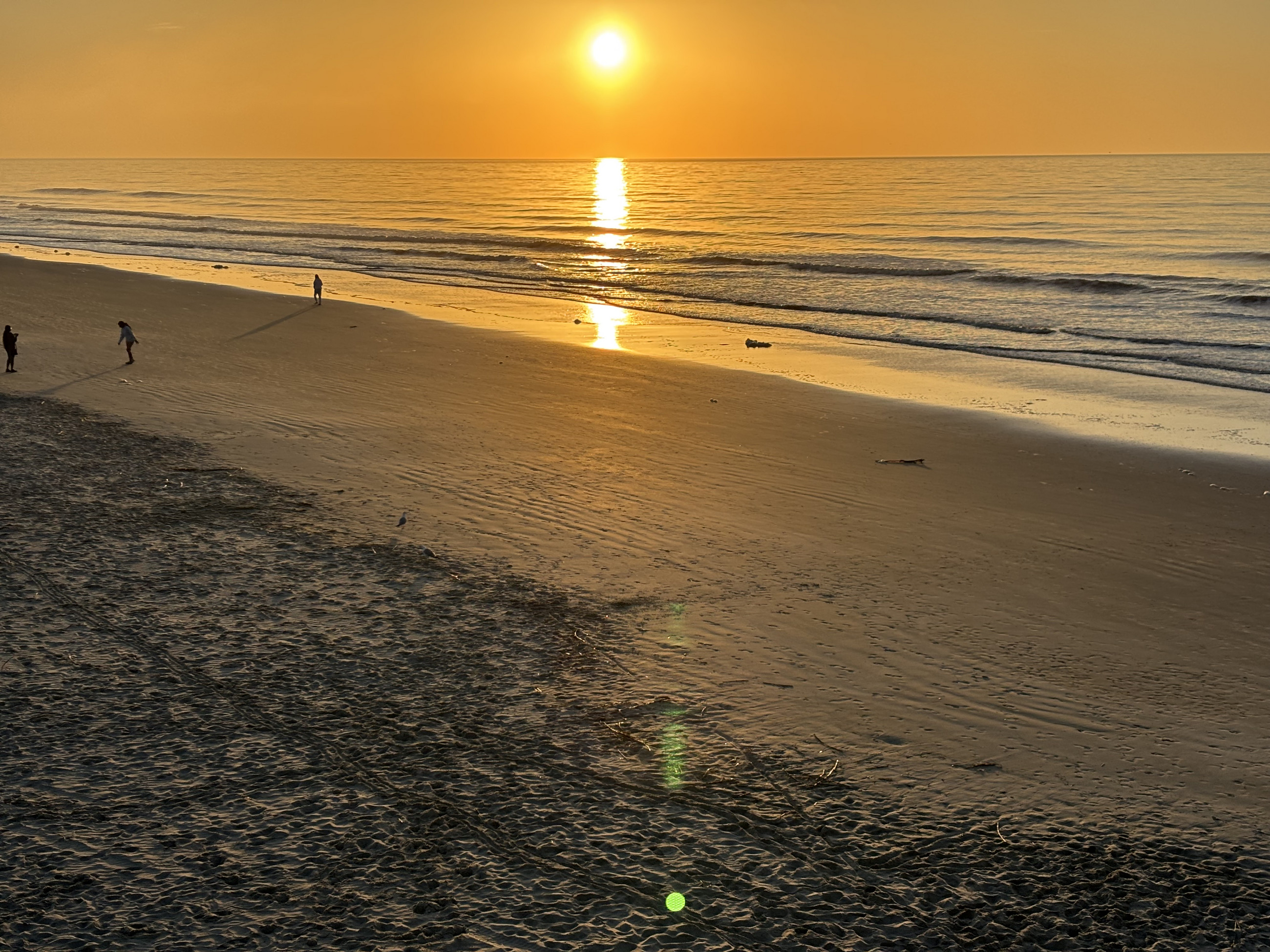 A golden sunrise lays a brilliant path across the Atlantic and wet sand at Folly Beach