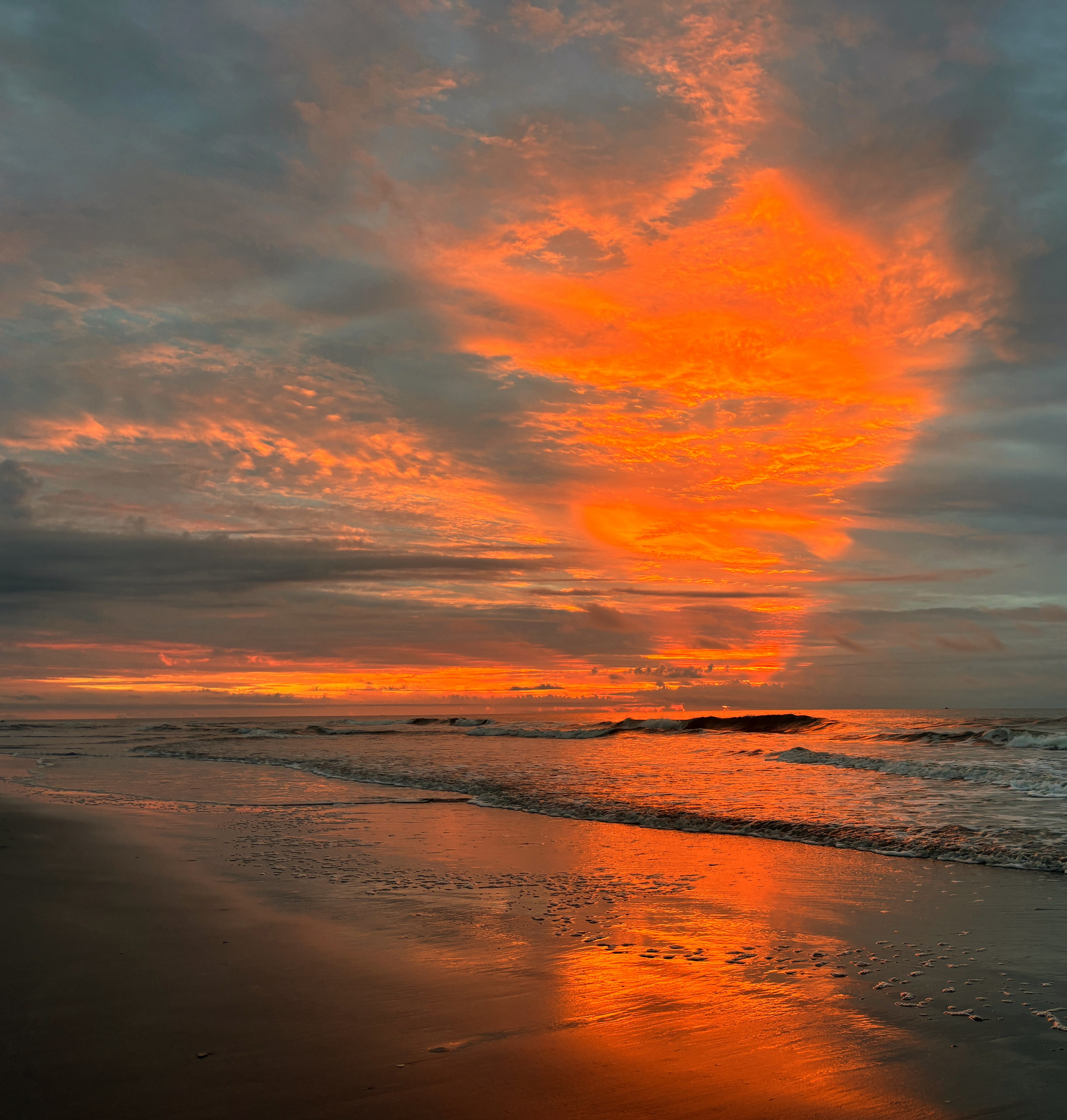 Molten Horizon: an orange pillar-shaped cloud reflected vertically through a dark morning shoreline